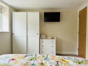 a bedroom with a bed with a dresser and a tv at The Retreat in Eccleston