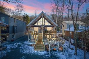 a house with a deck and stairs in the snow at New Luxury Lakeview Retreat with Lake Access, HotTub, Game Room, Sleeps 28 in Lake Harmony