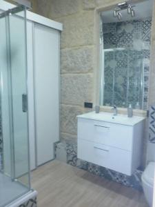 y baño con lavabo blanco y ducha acristalada. en Piso con vistas a 30m playa ALOJAMIENTOS VACAY, en Bueu