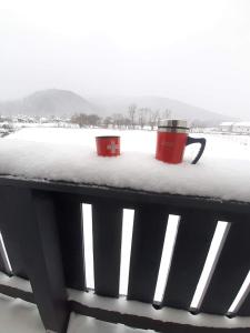zwei Tassen auf einer schneebedeckten Bank in der Unterkunft DOM HILLS Bucovina in Gura Humorului