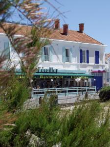 um edifício branco com um restaurante na praia em Hôtel L'Ecailler em La Cotinière