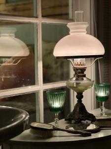 a lamp sitting on a table with two green glasses at HotelletDalkarlsberg in Gyttorp +39 photos
