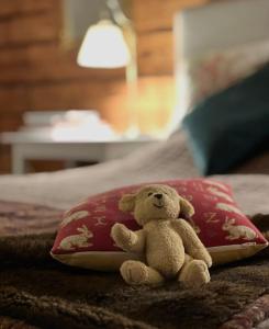 a teddy bear sitting on a bed with a red pillow at HotelletDalkarlsberg in Gyttorp