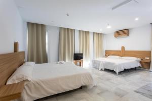 a hotel room with two beds and a television at Hotel El Tujjar in Los Barrios +46 photos