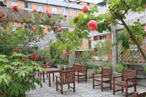 patio ze stołami i krzesłami oraz czerwonymi kwiatami w obiekcie Albergo Residence Italia Vintage Hotel w mieście Pordenone
