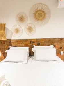a white bed with white pillows and a brick wall at Vila Tanrral in Lençóis