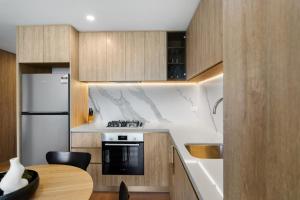 ゴールドコーストにあるThe Horizon - Brand NEW Casino 43F Luxury 2BR unit in Broadbeach with Pool Gym Netflixのキッチン(コンロ、冷蔵庫、テーブル付)