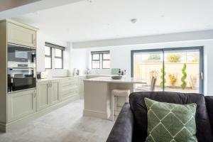 a kitchen with white cabinets and a couch in a room at The Lodge Private Parking & Garden in Cheltenham