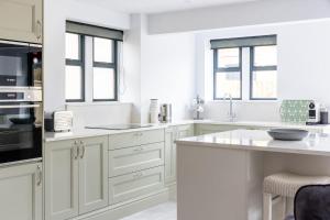a white kitchen with white cabinets and windows at The Lodge Private Parking & Garden in Cheltenham