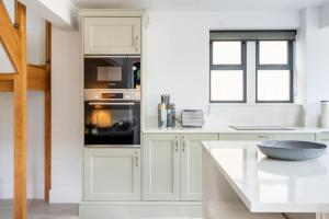 a kitchen with white cabinets and a bowl on a table at The Lodge Private Parking & Garden in Cheltenham