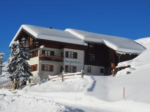 ein großes Gebäude im Schnee mit Schnee in der Unterkunft Familienbauernhof Burtscher in Fontanella