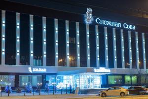 a building with cars parked in front of it at Snowy Owl Hotel in Krasnoyarsk