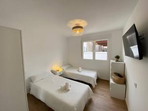 a white room with two beds and a television at Apartamento Trascuesta, PLENO CENTRO in Sanlúcar de Barrameda