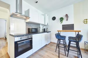 a kitchen with white cabinets and a table and stools at BE-4G - Joli 2 pièces tout équipé pour 1-2 pers au 4ème étage au centre de Mulhouse in Mulhouse
