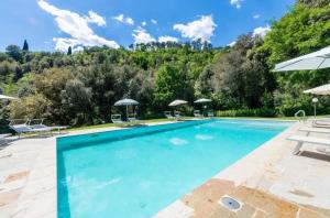 ローロ・チュッフェンナにあるCharming Studio with Shared Pool in Loro Ciuffennaの山のそばのプール(椅子、パラソル付)