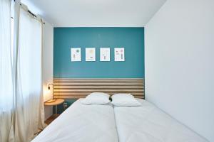a bedroom with a white bed with a blue wall at BE-4G - Joli 2 pièces tout équipé pour 1-2 pers au 4ème étage au centre de Mulhouse in Mulhouse
