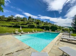 ローロ・チュッフェンナにあるCharming Studio with Shared Pool in Loro Ciuffennaの青い水と椅子のある大きなプール
