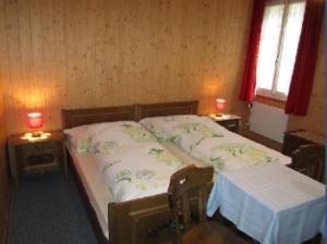 ein Schlafzimmer mit einem Bett mit zwei Tischen und zwei Fenstern in der Unterkunft Hotel Montana in Seelisberg