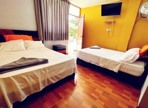 Una habitación de hotel con dos camas y un televisor. en LOS PECANOS Ica, en Ica