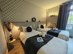a hotel room with two beds and a window at Logis Loire Hotel - Les Cocottes Restaurant in Les Rosiers
