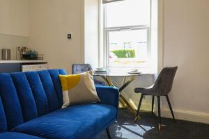 a blue couch in a living room with a table at 1-Bed Apartment with Sofa Bed in West Kilbride - Long Stays - Free Parking in West Kilbride +6 photos