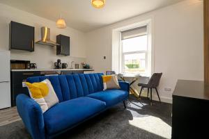 a blue couch in a living room with a kitchen at 1-Bed Apartment with Sofa Bed in West Kilbride - Long Stays - Free Parking in West Kilbride