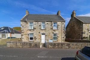 an old brick house with a white door on a street at 1-Bed Apartment with Sofa Bed in West Kilbride - Long Stays - Free Parking in West Kilbride