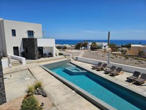 a villa with a swimming pool in front of a house at myLithos Suites in Monolithos