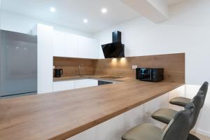 a kitchen with white cabinets and a wooden counter top at Apartman Svila in Đakovo