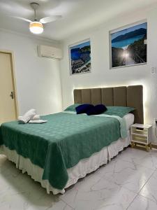 a bedroom with a large bed with a green comforter at Flats Mirassol in Arraial do Cabo