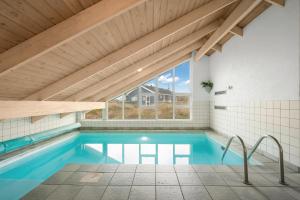 une piscine dans une maison avec un plafond en bois dans l'établissement Pool House With Spa And Sauna, 200 Meters From The North Sea, à Frøstrup