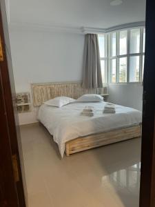 a bed in a white room with a window at Les persiennes usées in Sfax +2 photos