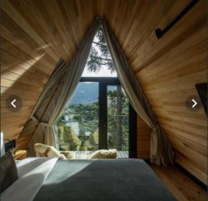 a room with a bed with a large window at La Mansarda Hotel in Urubici
