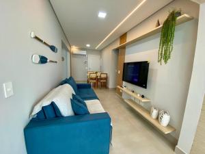 a living room with a blue couch and a tv at Residencial Acqua mare in Samaritá