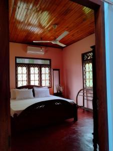 a bedroom with a bed and two windows and a ceiling at Golden Glade in Weligama
