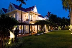 a large white house with a lawn at night at Homm Souvannaphoum Luang Prabang, part of Banyan Group in Luang Prabang