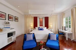 a bedroom with a large bed and blue chairs at Homm Souvannaphoum Luang Prabang, part of Banyan Group in Luang Prabang