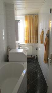 ein weißes Badezimmer mit einem Waschbecken, einer Badewanne und einem Waschbecken in der Unterkunft Ferienwohnung Schütze in Dresden