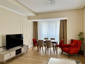 a living room with a table and chairs and a television at Prime Suites in Bishkek