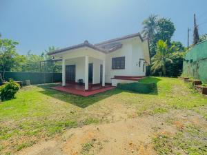a small white house with a yard at Golden Glade in Weligama