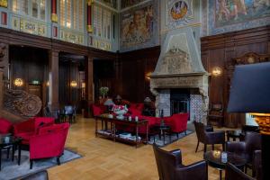 a living room with red chairs and a fireplace at Schlosshotel Münchhausen in Aerzen