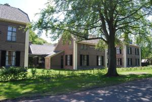 Veenhuizen苦与甜酒店的一栋前面有棵树的建筑物