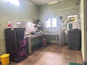 a kitchen with a sink and a refrigerator in a room at Wild Villa Homestay in Sultan Bathery