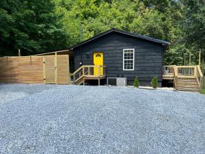 a black house with a yellow door and a fence at Flat Fenced Yard, Hot Tub, Wifi, Pool Table in Sevierville