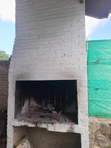 ein weißer gemauerter Kamin mit einer Bank darin in der Unterkunft Cabañas La Petunia in Santa Rosa de Calamuchita
