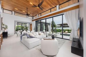 a living room with white furniture and large windows at Luxury 3BR Villa Eden with Private Pool by TropicLook in Ban Pak Lak