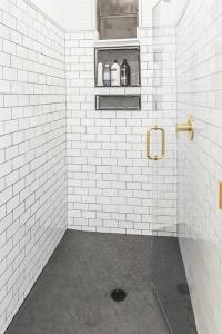 a white tiled bathroom with a shelf with bottles on it at Historic Park Place Retreat - 3 Bdrm on the Park! in Columbus +40 photos