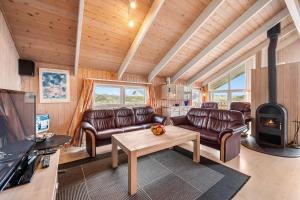 Elle comprend un salon doté d'un mobilier en cuir et d'un plafond en bois. dans l'établissement Pool House With Spa And Sauna, 200 Meters From The North Sea, à Frøstrup