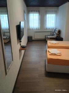 a room with two beds and a flat screen tv at Къща за гости Билдникс in Malko Tŭrnovo