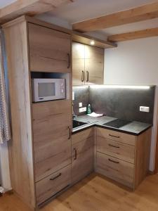 una cucina con armadi in legno e forno a microonde di Ferienwohnung Lippenlehen a Marktschellenberg